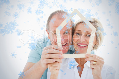 Happy older couple holding house shape