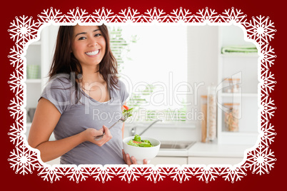 Attractive pregnant woman holding a bowl of salad while standing