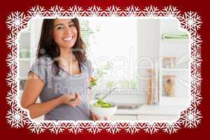 Attractive pregnant woman holding a bowl of salad while standing