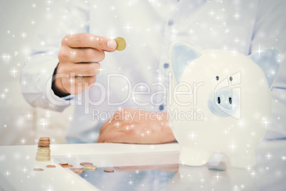 Mid section of a man putting some coins into a piggy bank