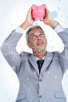 Composite image of curious businessman holding piggy bank above his head