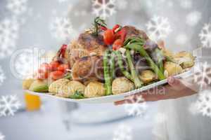 Composite image of woman presenting a roast dinner