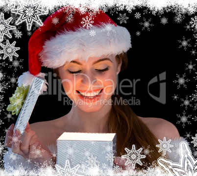 Pretty redhead in santa outfit opening a gift