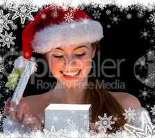 Pretty redhead in santa outfit opening a gift