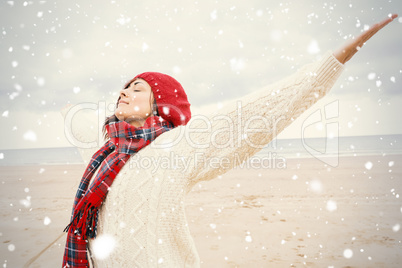 Woman in warm clothing stretching her arms at beach