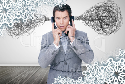 Overworked businessman holding two telephones