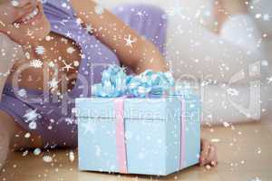 Smiling woman holding a present lying on the floor