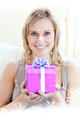Composite image of handsome woman holding a present in a living
