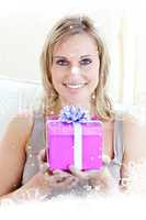Composite image of handsome woman holding a present in a living