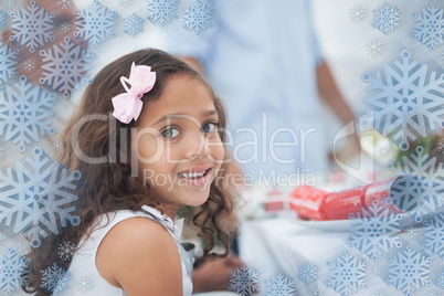 Composite image of little girl sitting at table for christmas di
