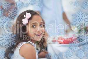 Composite image of little girl sitting at table for christmas di