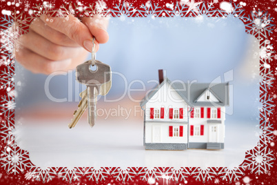Woman holding keys next to a model house