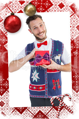 Composite image of geeky hipster offering christmas gift