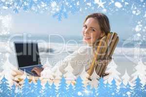 Gorgeous blonde sitting on deck chair using laptop on beach