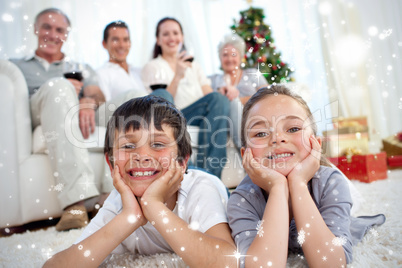 Brother and sister on floor with their family in christmas