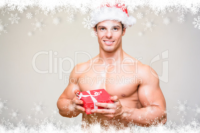 Composite image of shirtless macho man in santa hat holding gift