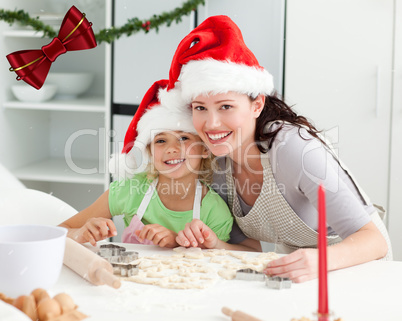 Portrait of a cute girl with her mother baking christmas cookies