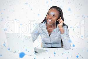 Smiling businesswoman making a phone call while using a laptop