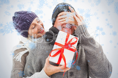 Happy mature woman hiding gift from partner