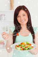 Redhaired woman enjoying a mixed salad in the kitchen