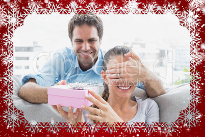 Man surprising his girlfriend with a pink gift on the sofa