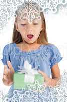 Composite image of surprised little girl holding a wrapped gift