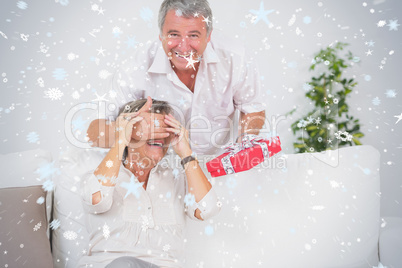 Composite image of old man hiding eyes of his wife for a gift