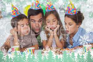 Composite image of family blowing candles together