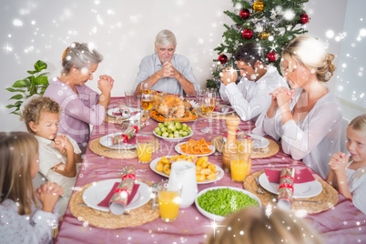 Composite image of family saying grace before christmas dinner