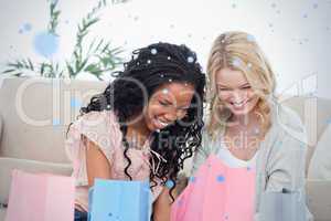 Two smiling women sitting on the floor with shopping bags