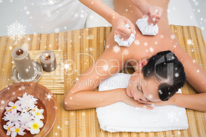 Peaceful brunette enjoying a herbal compress massage