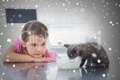 Composite image of girl looking at kitten drinking milk from bow