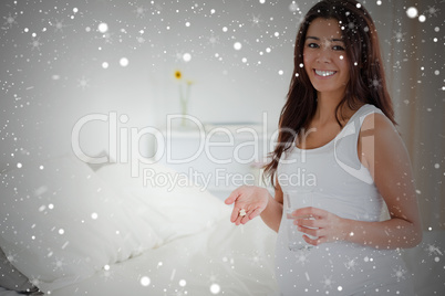 Beautiful pregnant woman holding a glass of water and pills whil