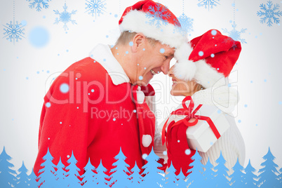 Festive older couple smiling at each other and holding gift