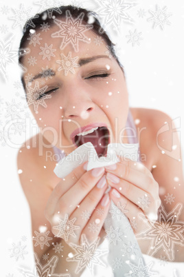 Woman sneezing into a tissue