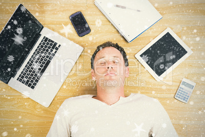 Composite image of casual tired man lying on floor