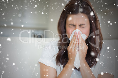 Composite image of brunette sneezing in a tissue