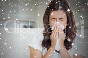 Composite image of brunette sneezing in a tissue