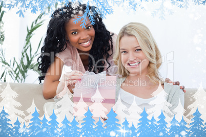 Woman holding a present is smiling at the camera with her friend