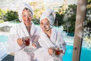Smiling women in bathrobes having tea
