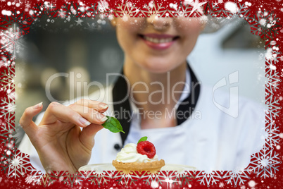 Smiling head chef putting mint leaf on little cake on plate