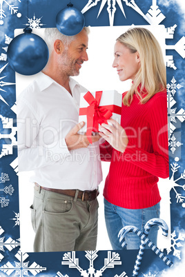Composite image of smiling couple embracing and holding gift