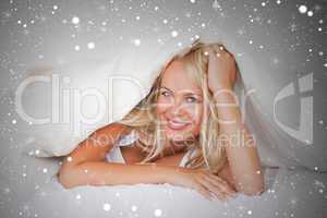Composite image of smiling woman under a duvet