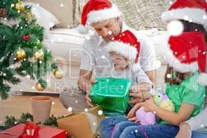 Happy family looking at the little boy opening a christmas prese