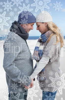 Attractive couple standing on the beach in warm clothing