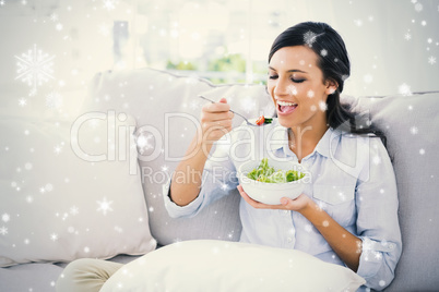 Happy woman relaxing on the sofa eating salad