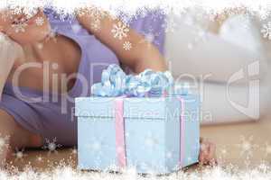 Composite image of smiling woman holding a present lying on the