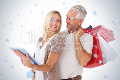 Happy couple holding shopping bags and looking at tablet pc