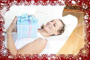 Charming blond woman holding a present lying on a sofa