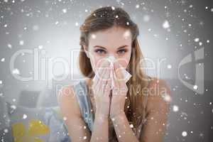 Sick young woman sitting on sofa blowing her nose